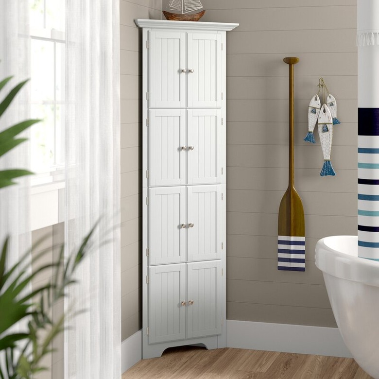 White 8-door corner bathroom cabinet in coastal-themed bathroom with tub and hardwood floors