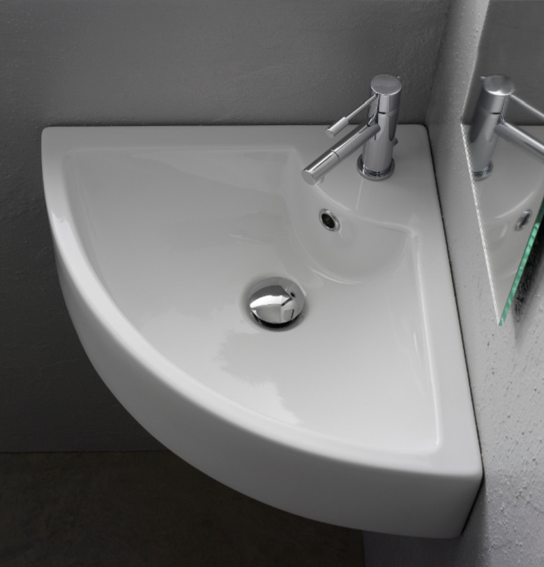 White ceramic corner bathroom sink with silver hardware in gray bathroom