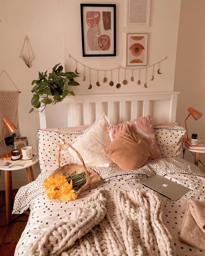 bedroom with moon-phase wall-hanging and basket of flowers on bed