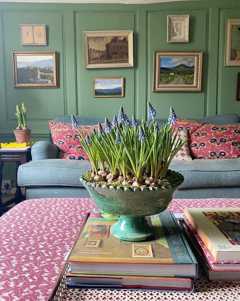 living room with artwork in gold frames on green wall