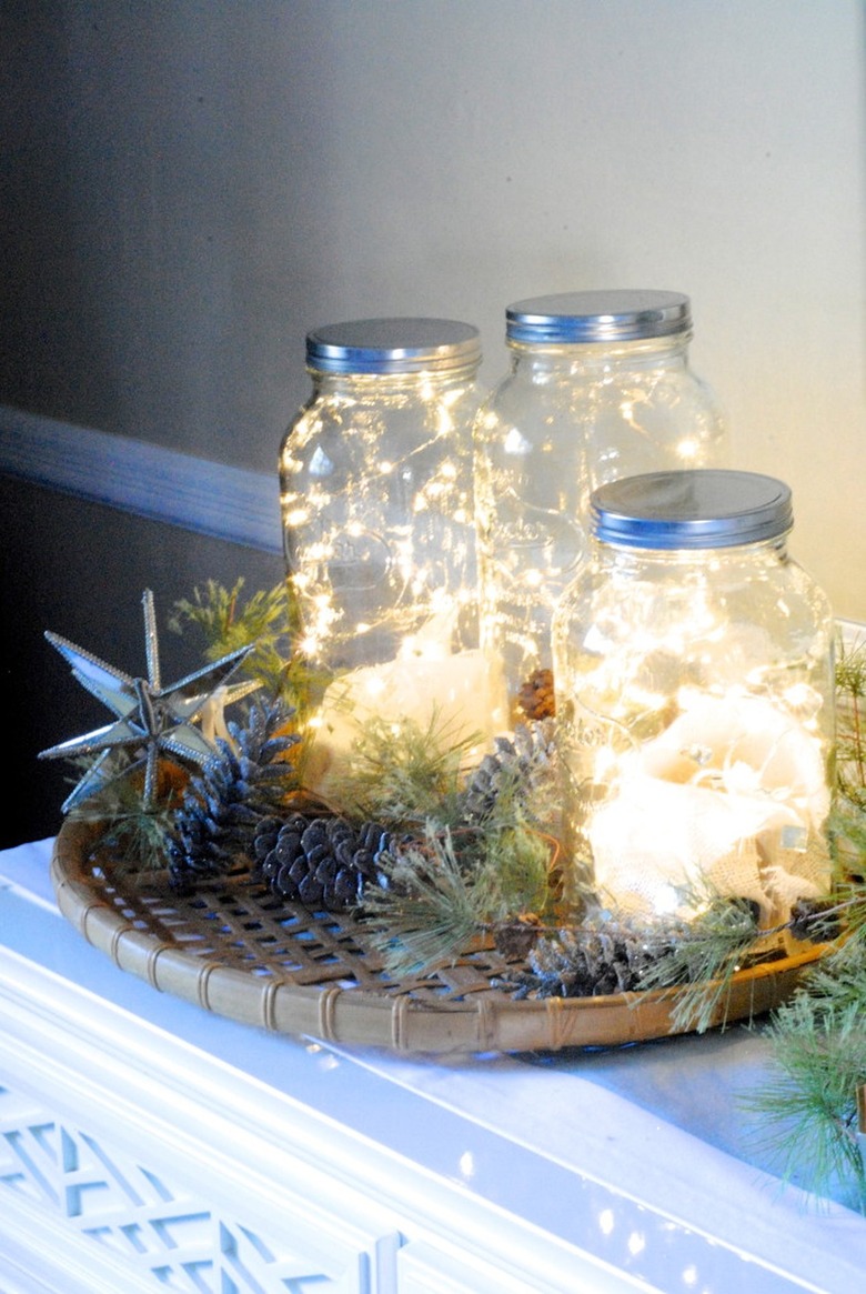 Vignette of fairy lights in mason jars surrounded by pinecones