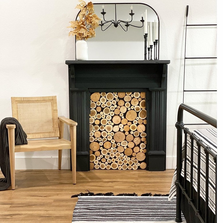 Bedroom with faux fireplace with wood blocks inside and mantle decked with a mirror