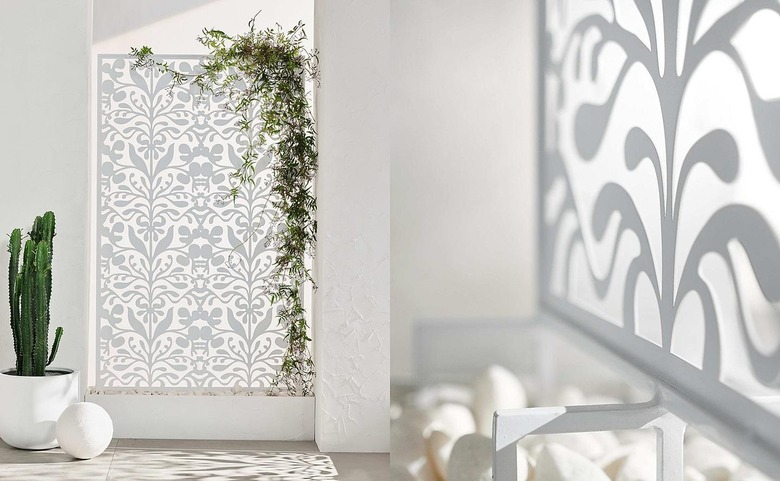 A white metal trellis in a courtyard with a cactus