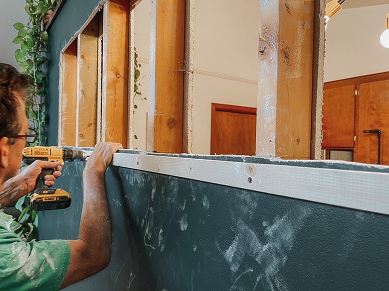 Screw a stabilizing piece of wood to the studs to keep them steady while you saw through them.