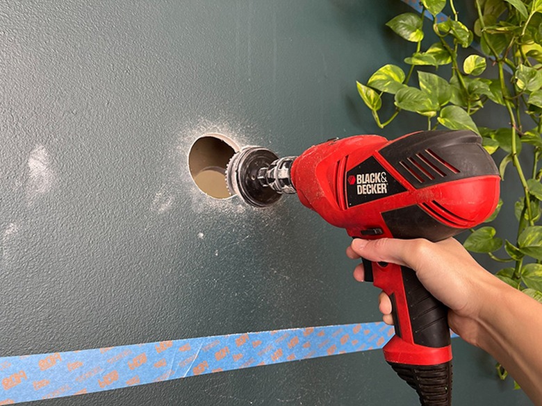 Cut exploratory holes through the drywall using a hole saw attached to a drill.