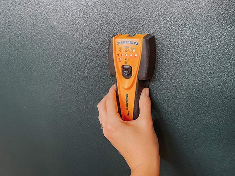 Use a stud finder to locate studs and possible electrical wires hidden behind the spot you want to put your cutout.