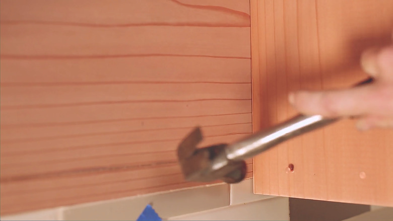 Hammering copper nails to redwood side board