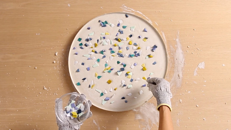 Spreading broken glass tiles over concrete for terrazzo table