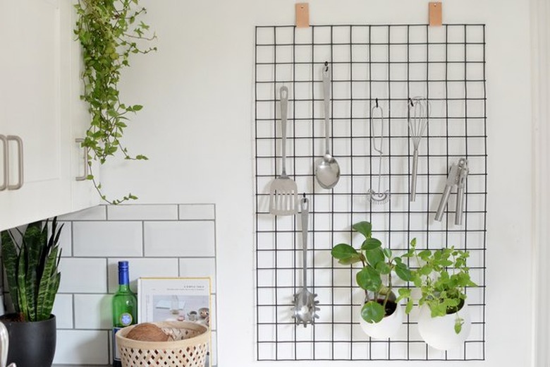 Grid wall organizer with kitchen utensils.
