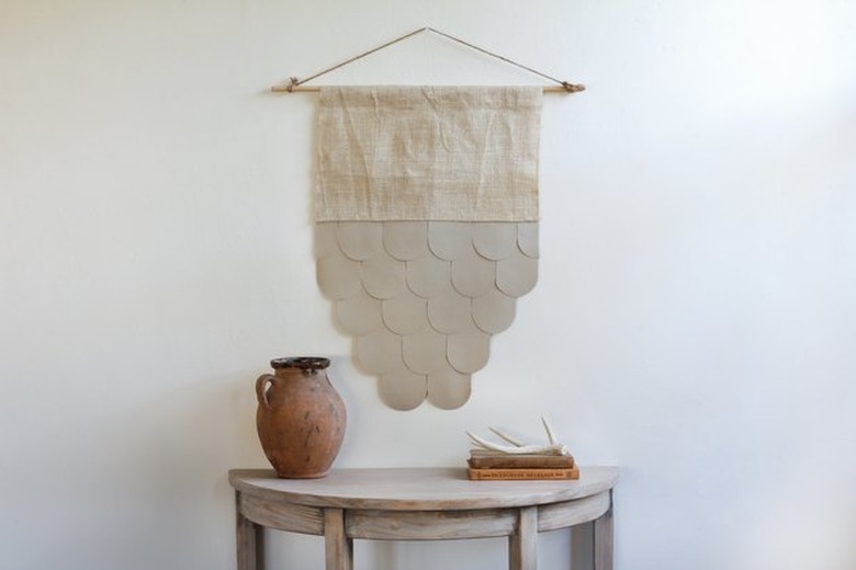 Leather and burlap wall hanging over wood table.