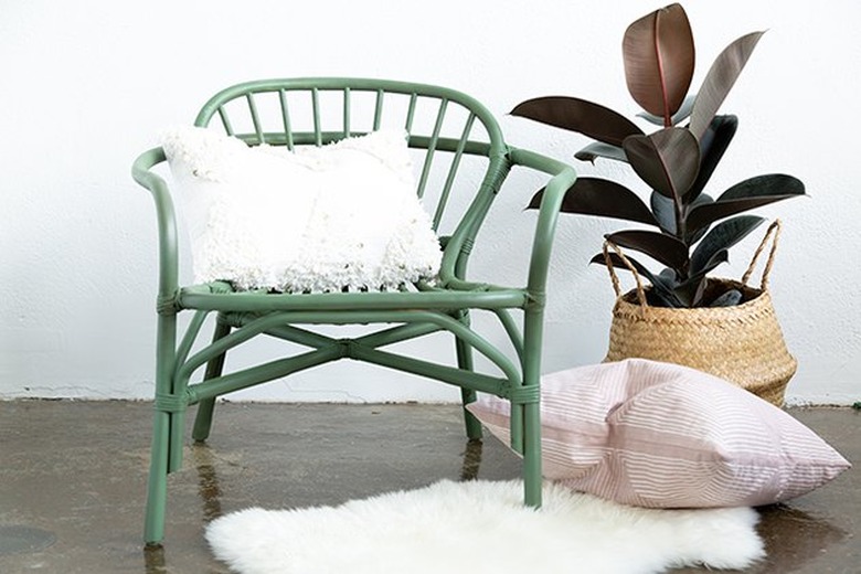 Green painted rattan chair with boho basket and plant