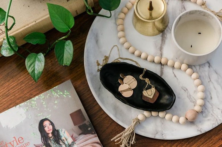 Black air-dry clay dish with jewelry on marble tray.