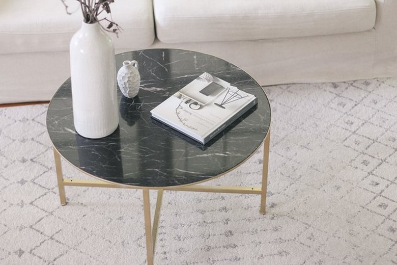 Marble top coffee table with brass legs in living room.