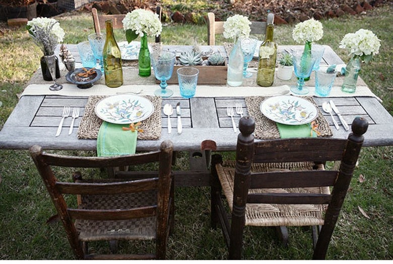 Vintage barn door repurposed as dining table with two wood chairs and table set with flowers and glassware