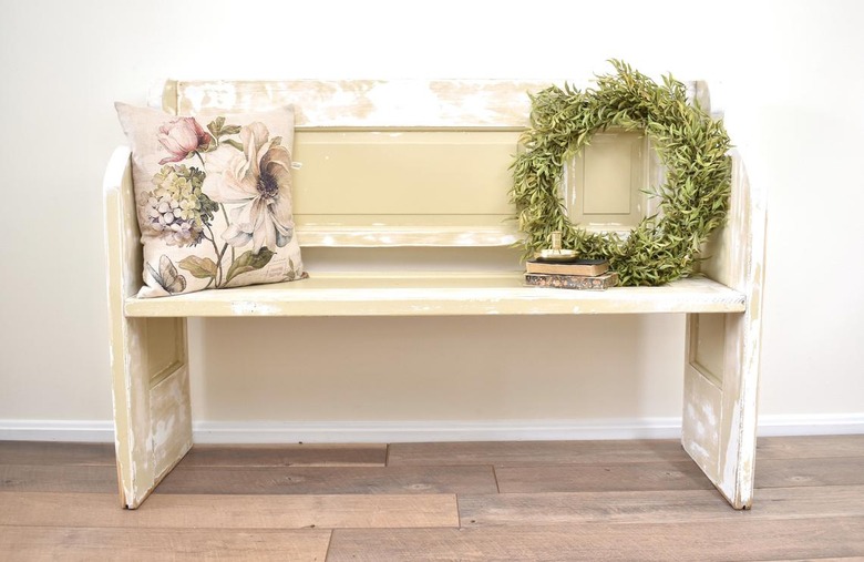 Cream and beige hallway bench made of vintage doors with pillow and wreath on seat