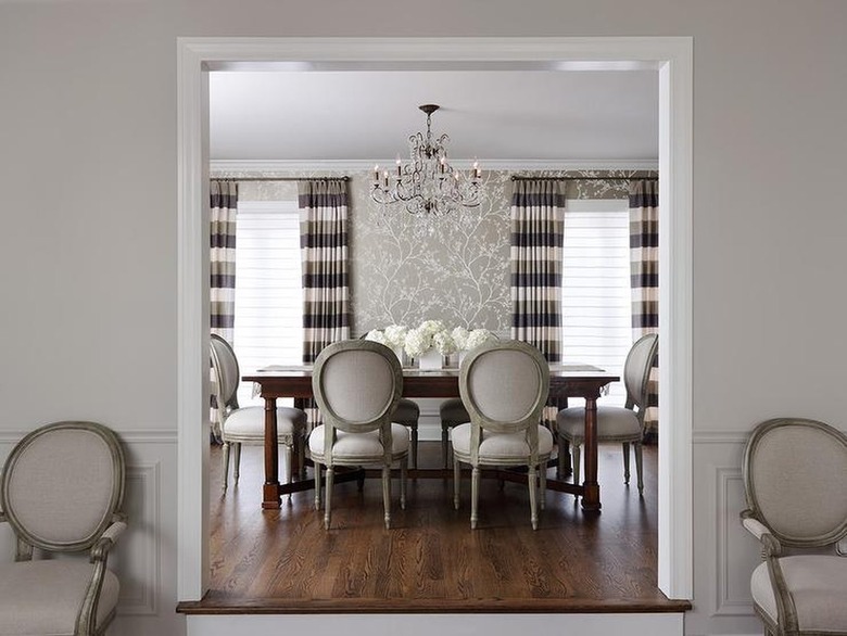 Dining room with gray patterned wallpaper and gray and black striped curtains.