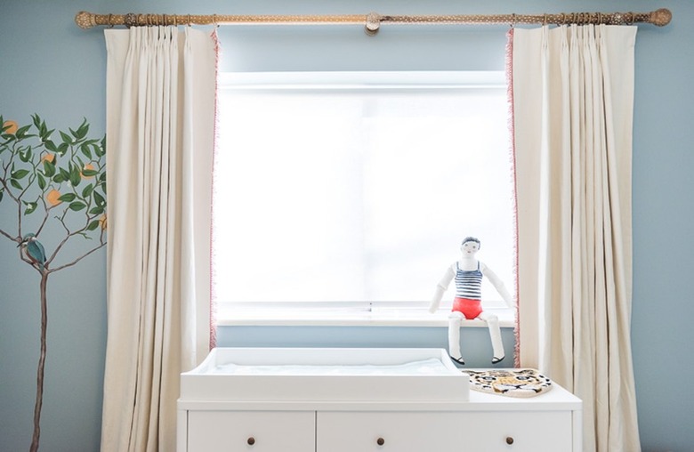 A sky blue nursery with cream curtains.