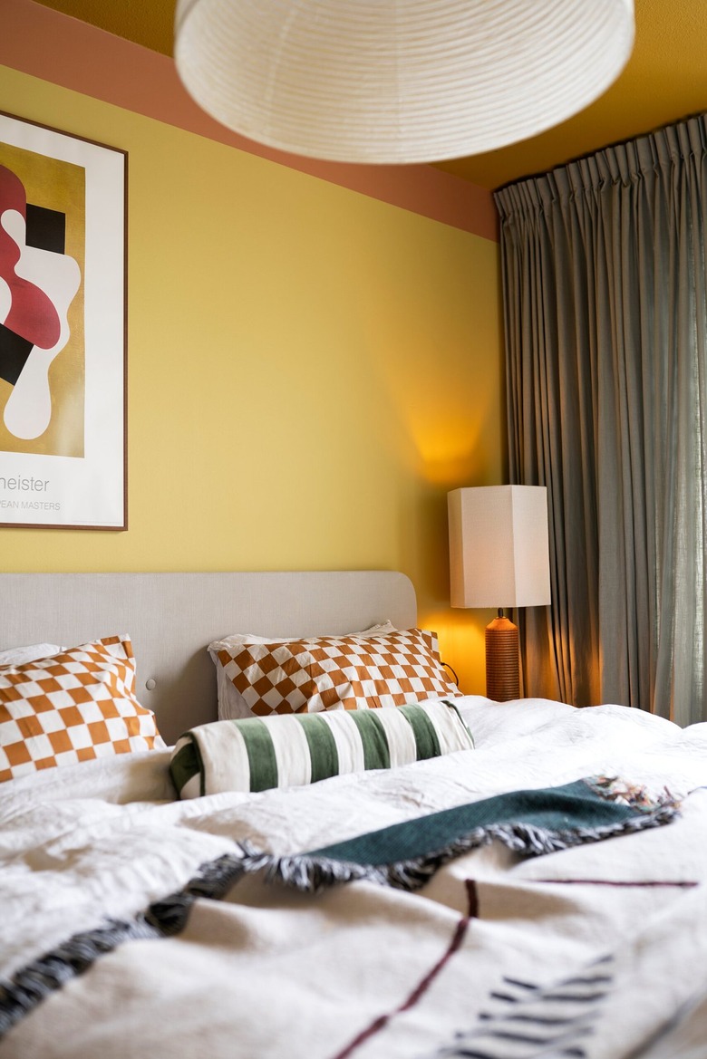 A modern and layered bedroom with orange checkerboard pillows
