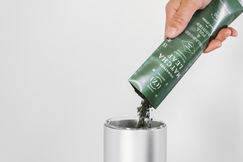 person pouring leaves from packet into machine