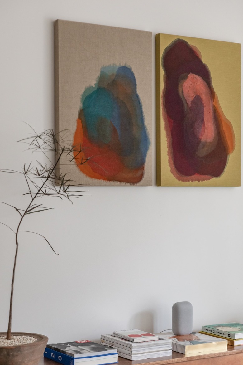 A diptych by Tony DeVoney hanging on the wall above bench filled with books