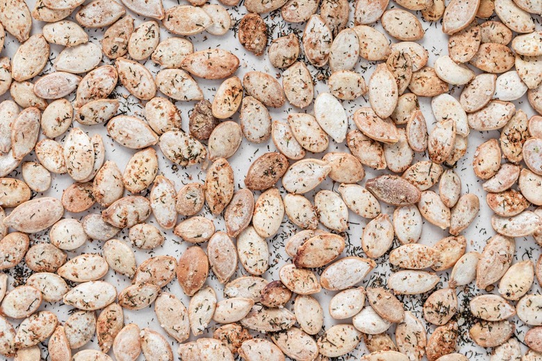 A close-up of the golden brown dill pumpkin seeds on the parchment paper.