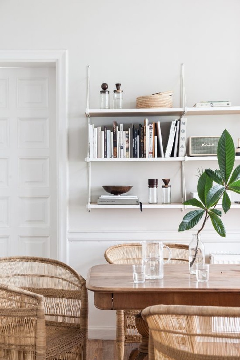 dining room with wall-mounted shelving and woven equipale chairs