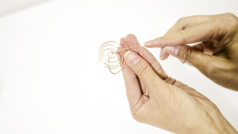 pulling the end of a copper wire through a spiral that has been twisted at the other end