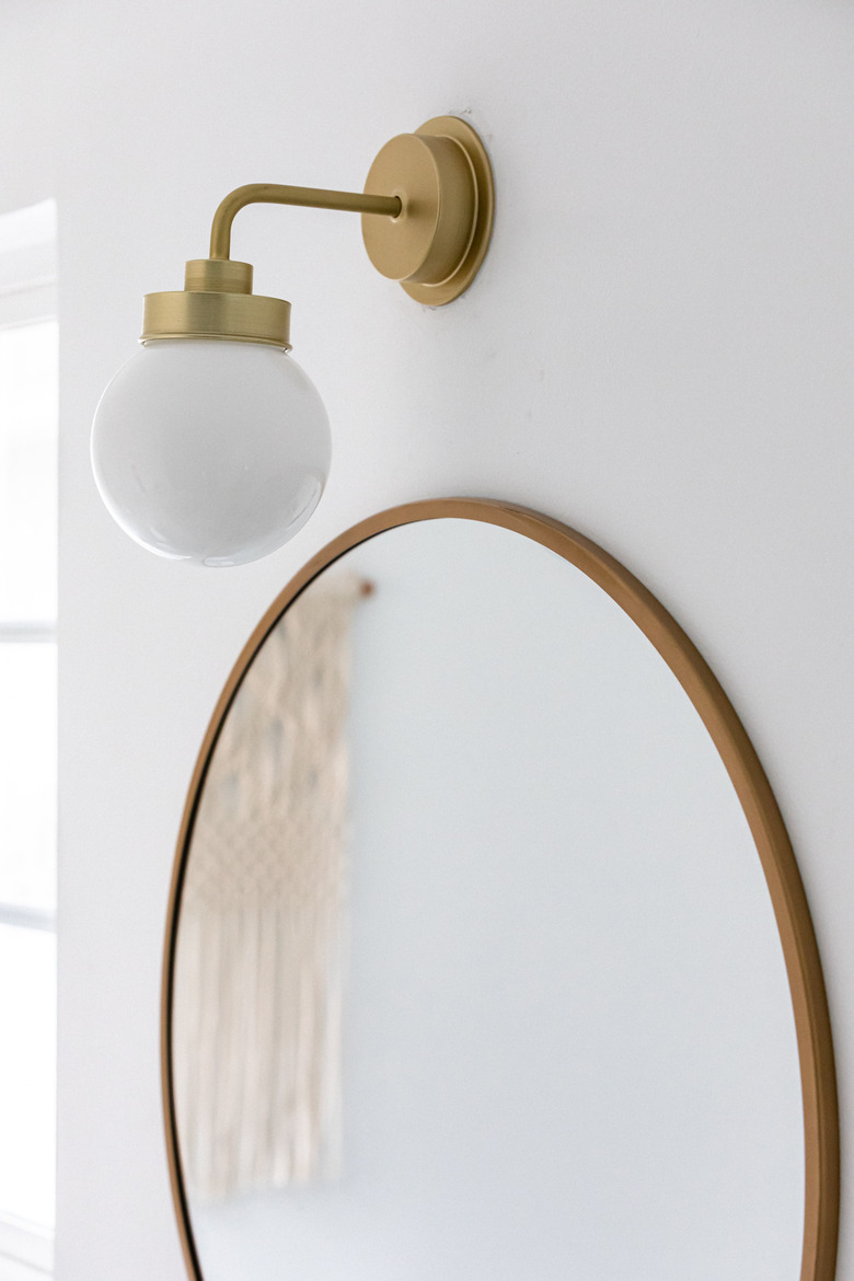 bathroom bulb light over a circular mirror with brass trim