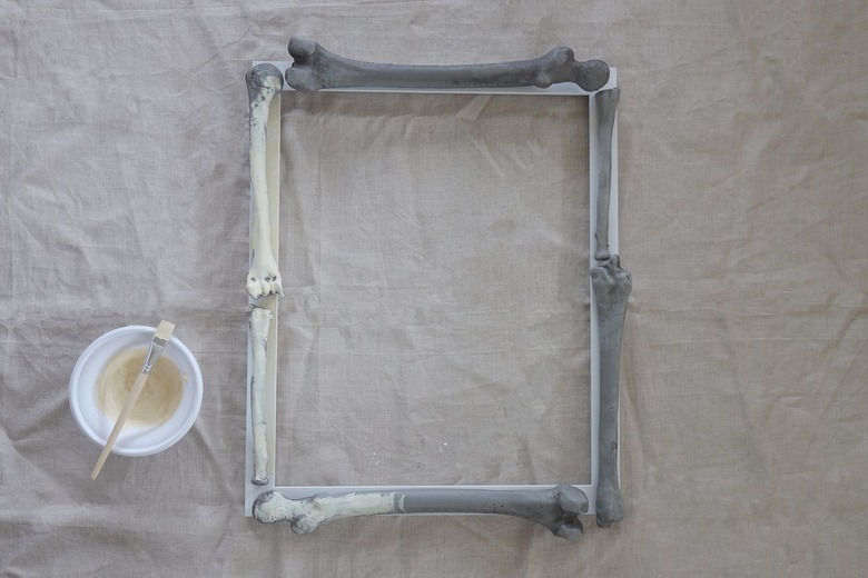 Painting plastic bones on frame with an ivory-hued plaster paint