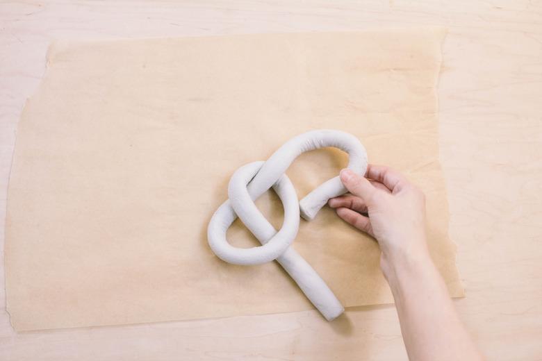 Shaping tube of air dry clay into a knot