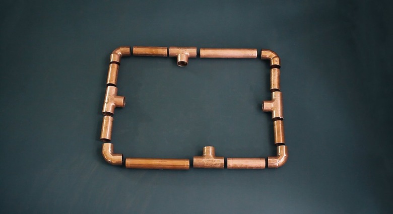 pieces of copper pipe laid out on a table in nearly their final position