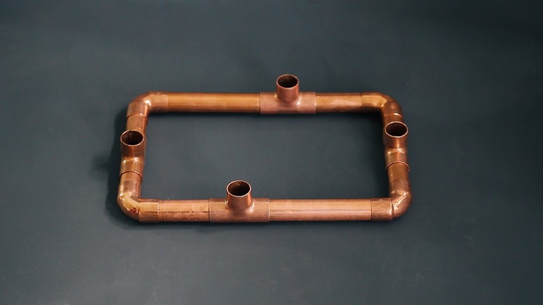 a rectangular copper candelabra base made from copper pipe