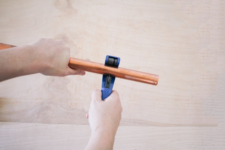 using a pipe cutter to trim a section of copper pipe