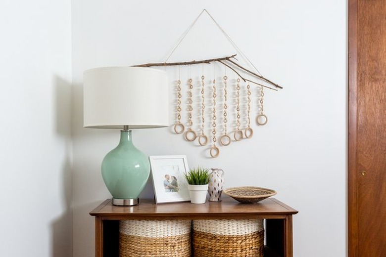 Wood wall hanging over console table and mint green lamp