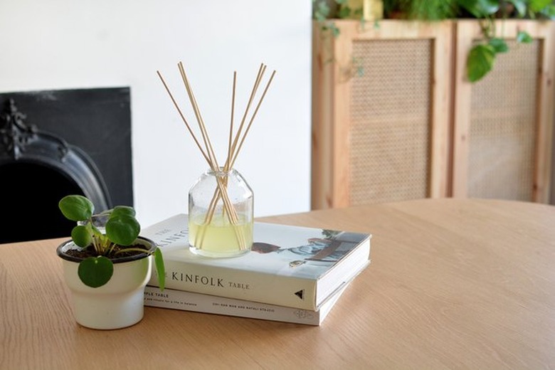 Reed diffuser on table with stack of books