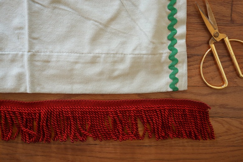 Brick red bullion fringe trim cut longer than width of velvet curtain panel