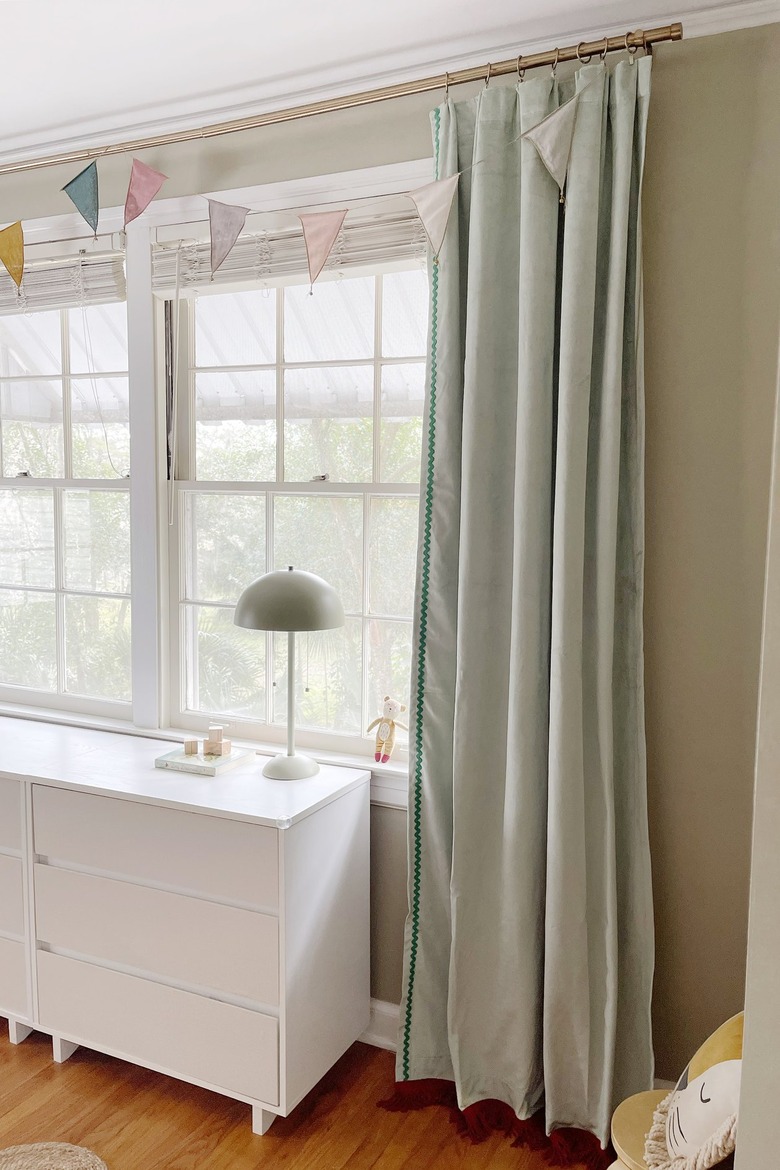 Sage green velvet curtains with brick red fringe trim on the bottom and emerald green rick rack trim on the side