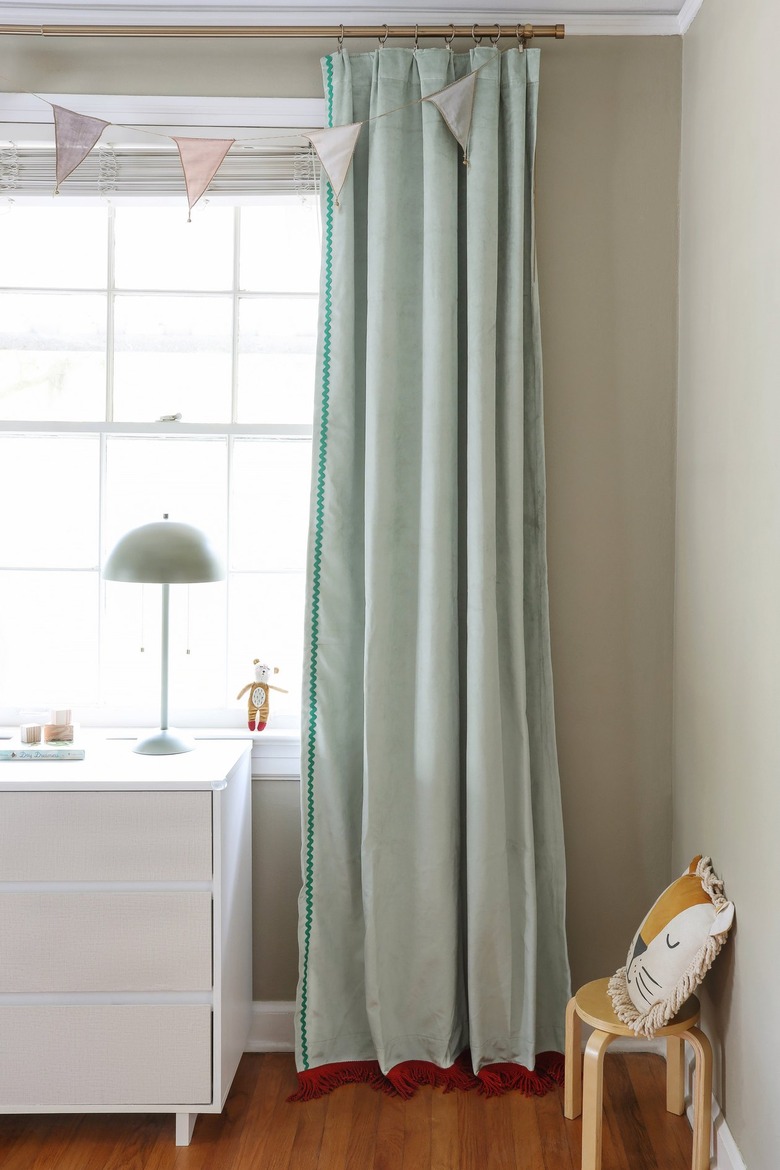 Sage green velvet curtains with brick red fringe trim on the bottom and emerald green rick rack trim on the side