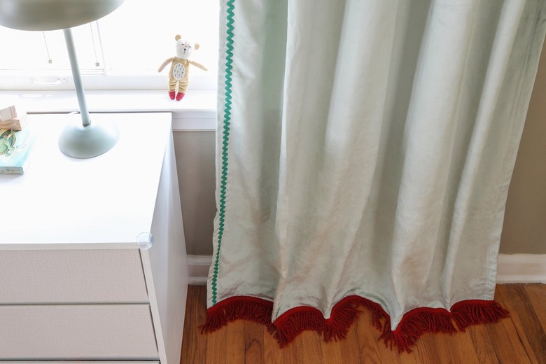 Sage green velvet curtains with brick red fringe trim on the bottom and emerald green rick rack trim on the side