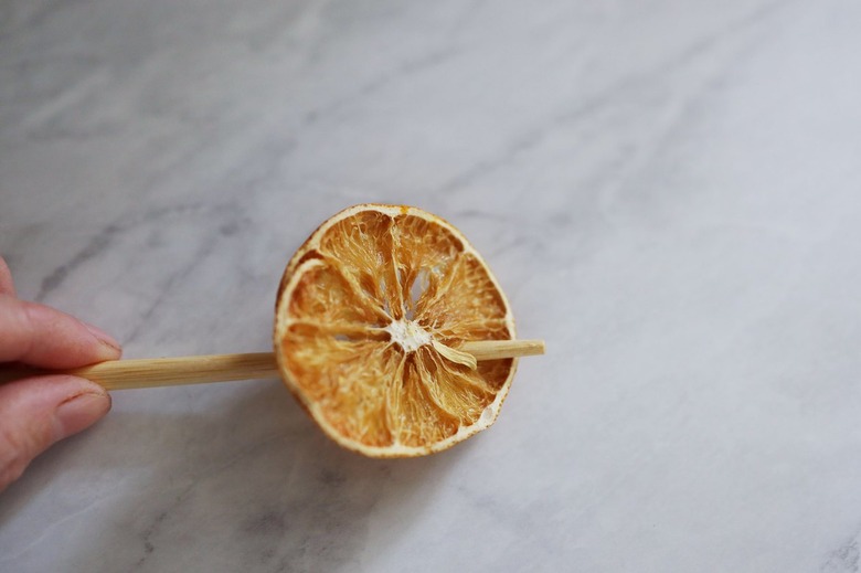 Poking hole through dried orange with wood skewer