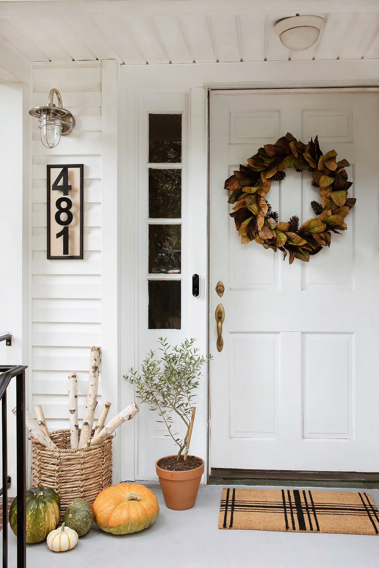 Faux magnolia wreath hung on door with plaid doormat