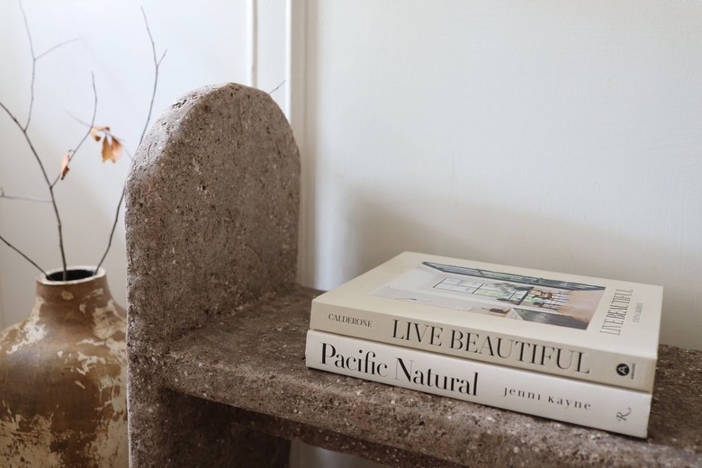 DIY limestone hypertufa bench in entryway with two books on top and a vase next to it