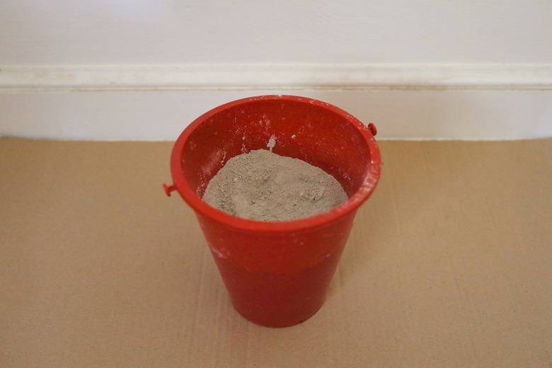 Dry cement mix in a red plastic bucket