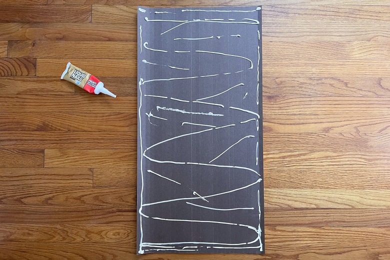 Construction adhesive piped onto back of pole wrap