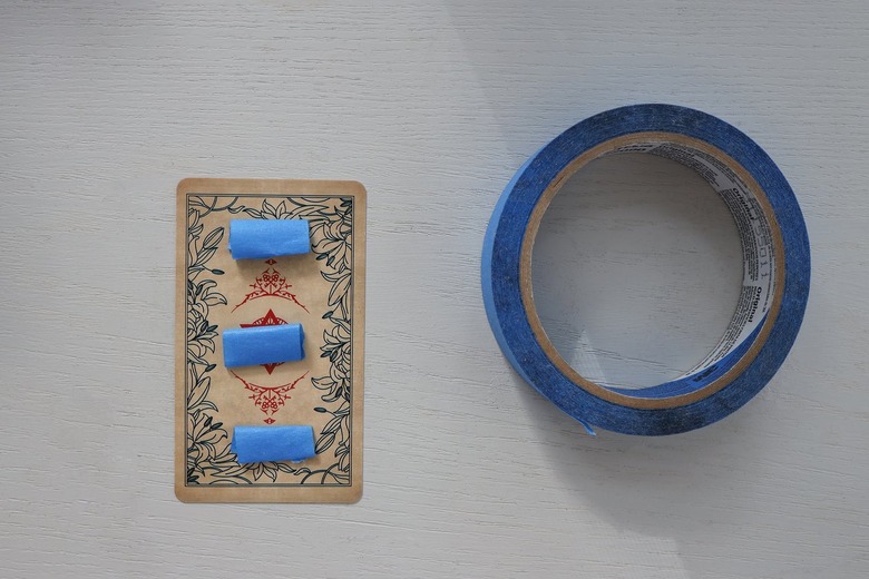 Three pieces of blue painter's tape rolled into strips and attached to back of tarot card