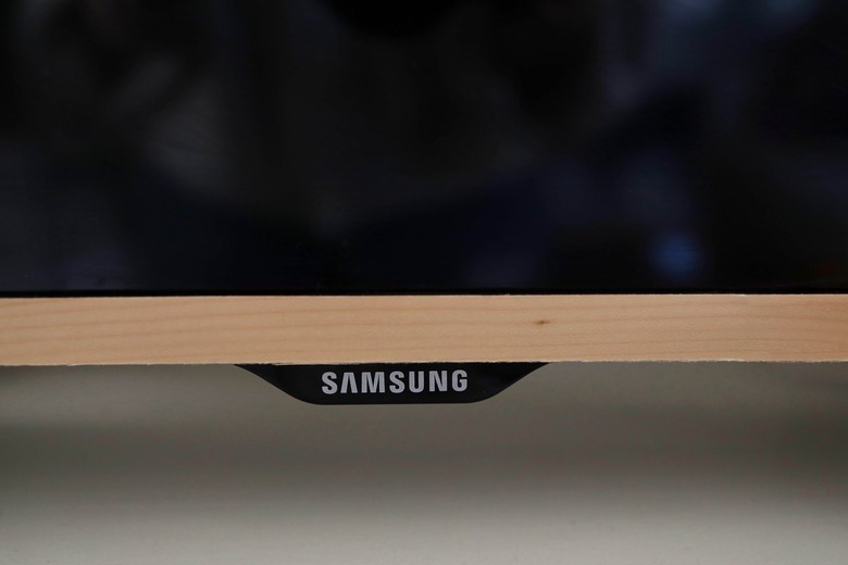 Pressing wood veneer to bottom of television trim