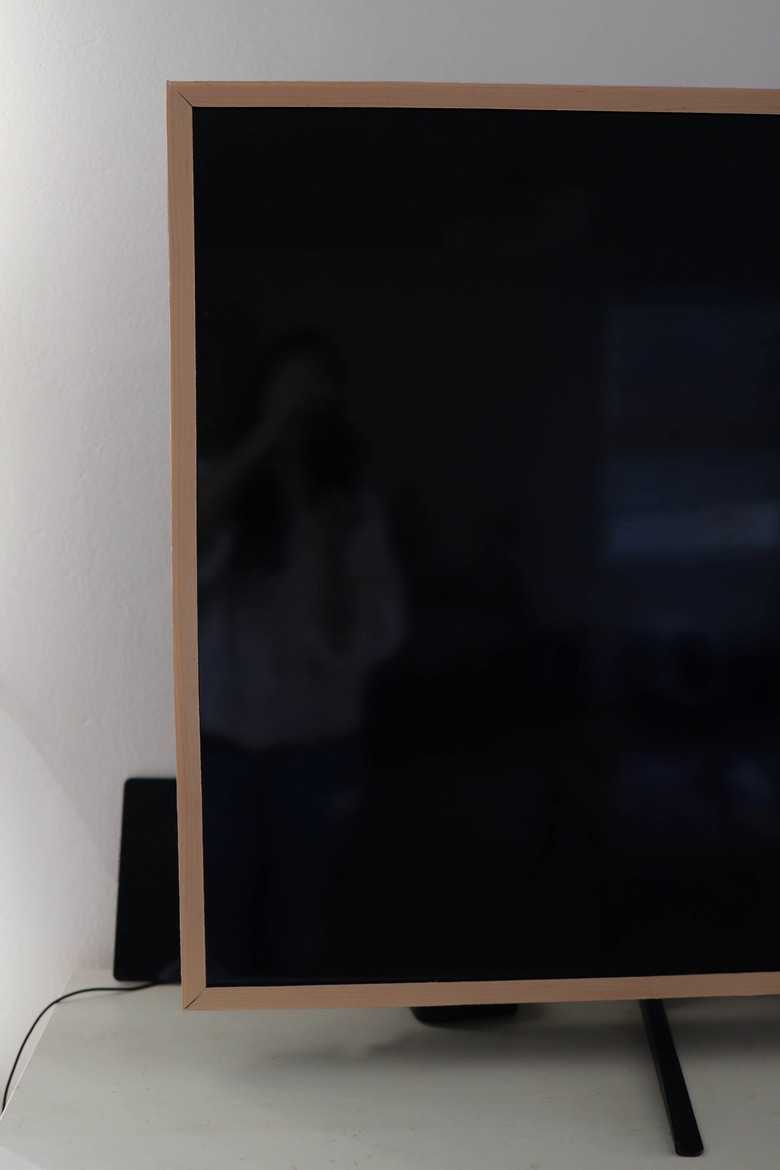 Wood veneer adhered around television trim