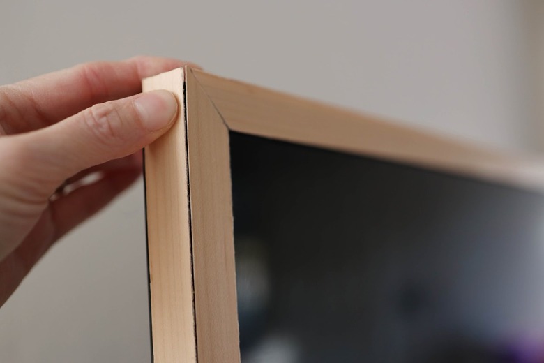 Pressing wood veneer to side of television trim