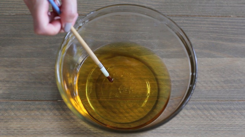 Paintbrush dipped in bowl of melted wax