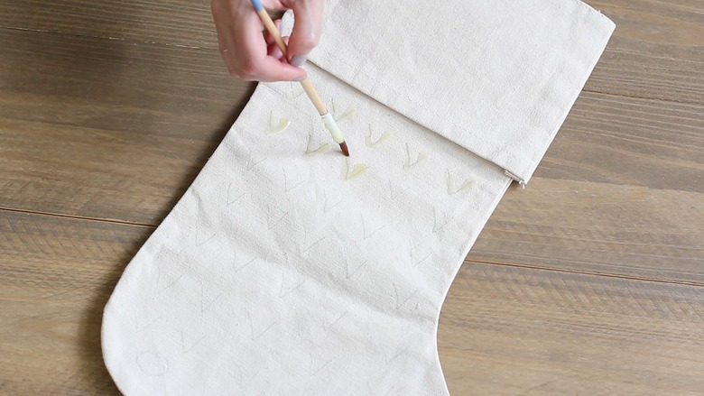 Hand painting wax design on white stocking with small paintbrush